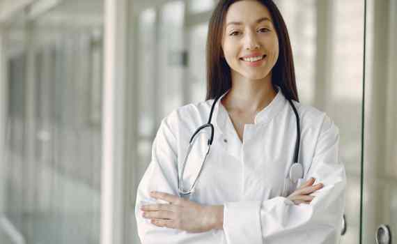 crop doctor in medical uniform with stethoscope standing in clinic corridor